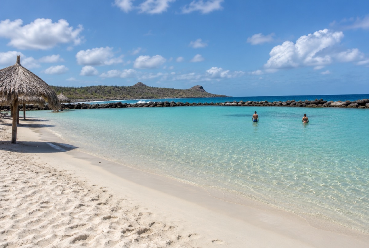 The calm turquoise lagoon of Baby Beach, Aruba, with the rock barrier at its mouth