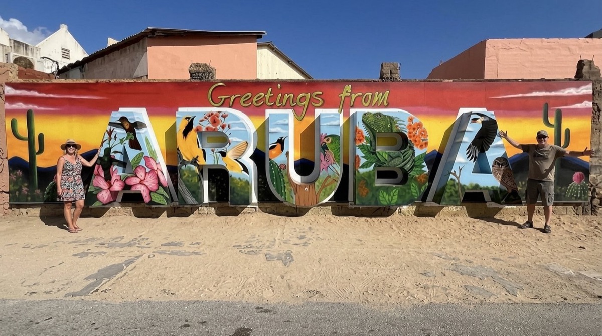 A couple at the Greetings from Aruba mural in San Nicolas